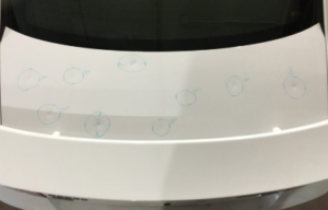 Car trunk with multiple hail dents marked for paintless dent repair