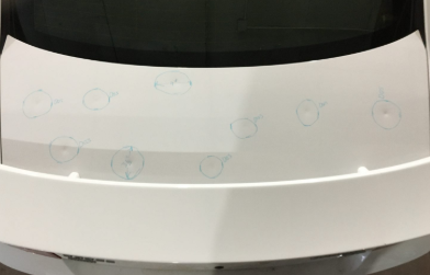 Car trunk with multiple hail dents marked for paintless dent repair